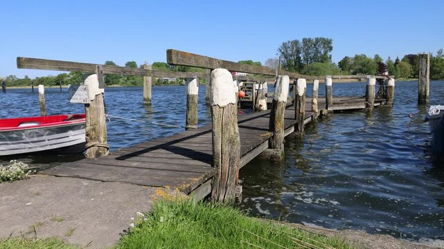 Tranquil river scene with wooden pier and distant houses on sunny day in Arnis a tiny City in Germany