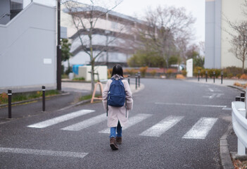 冬の朝の住宅街で通学中の一人の小学生の女の子の姿