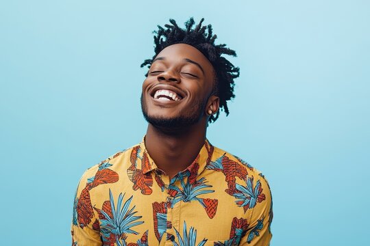 Joyful Black man in floral shirt, eyes closed, smiling broadly. Perfect for projects on happiness, summer, freedom, and positive emotions.