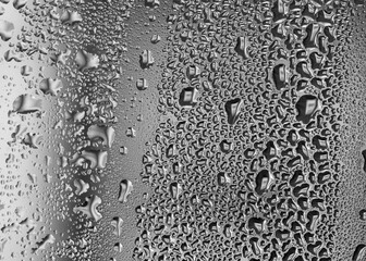 Monochrome pattern of water droplets on cold window glass
