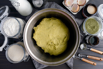 Green Matcha Bread Dough in a Mixing Bowl: Unrisen green tea babka dough in a mixing bowl surrounded with other bread ingredients and kitchen tools