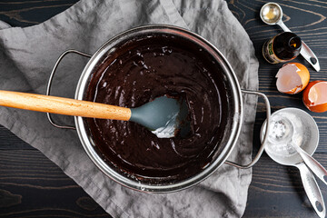 Brownie Batter Made with Melted Dark Chocolate in a Saucepan: Brownie batter mixed with silicone spatula in small pot with ingredients on the side