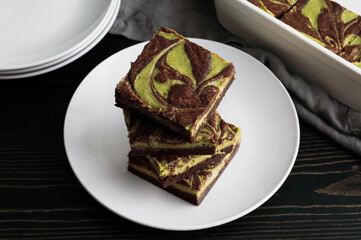 Stacked Matcha Cheesecake Brownies Angled View: Dark chocolate brownies with green tea cream cheese...