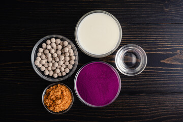 Purple Sweet Potato Bubble Tea Ingredients: Powdered sweet potato, tapioca balls, and more ingredients on a dark wooden table