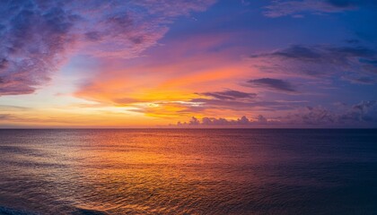 Fototapeta premium Vibrant sunset over the ocean, painting the sky with fiery hues of orange, purple, and pink.