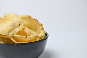 Close up and half view of chips Emping in the black bowl. Emping crackers made from melinjo fruit. Isolated on the white background. Copy space.