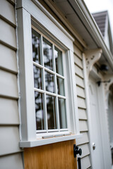 Elegant White Window and Wooden Door Detail on a Modern House Exterior. High-quality image showcasing beautiful home architecture and design. Ideal for real estate and home improvement websites.