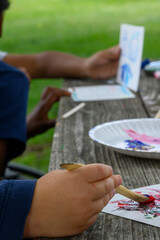 Close up of a group of children painting and showing off their art pieces. Teaching children empathy and responsibility at a Nature Preschool in Detroit, MI