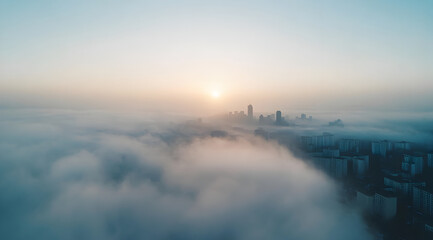 Naklejka premium A serene aerial view of a city skyline emerging through fog at sunrise, creating a tranquil and atmospheric scene.