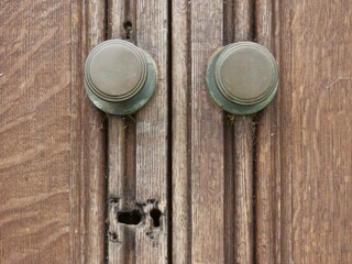 Fototapeta premium Two Weathered Bronze Doorknobs On Ancient Old Wooden Door With Damaged Keyhole Lock Patina Aged