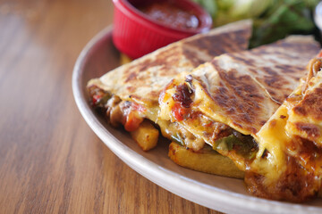 A Delicious Quesadilla accompanied by Fresh Salsa on a Rustic Wooden Table