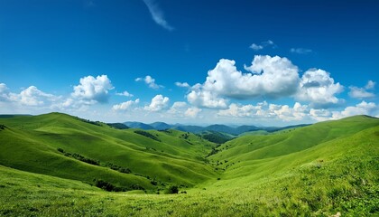 Naklejka premium A panoramic view of lush green hills under a bright blue sky dotted with fluffy clouds, showcasing natural beauty and tranquility.