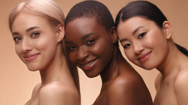 Three women stand closely together, showcasing their unique beauty and diverse skin tones. The warm background creates a vibrant atmosphere, highlighting their expressions and smiles.