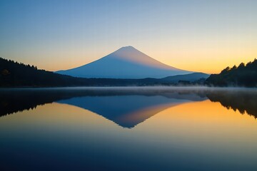 The shadow of a mountain peak on a nearby lake, reflected perfectly in the still water during sunrise.