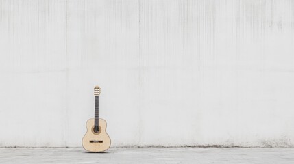 Acoustic guitar leans against a white wall.