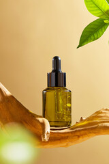 On a beige backdrop, a green amber glass bottle with a mockup of a serum is set in front of a piece...