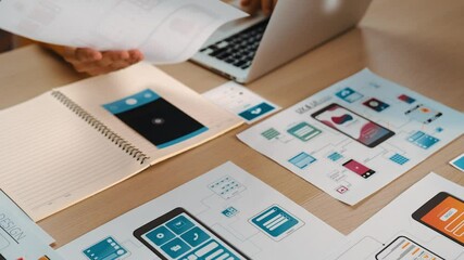 Hand focus of startup company employee present user interface prototype for mobile application to smart manager in office workspace. UX UI designer explain function of icon design on paper. Synergic