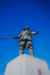 晴天の空に立つ長宗我部元親像、鎮守の森公園にて