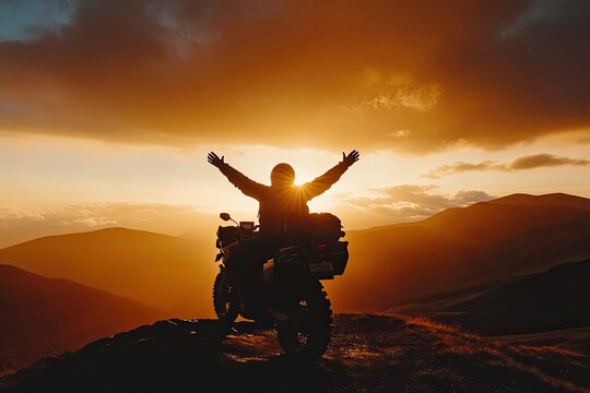 A silhouette of a man on his adventure motorcycle on the Transfagarasan, celebrating the end of an epic journey with arms raised in the sunset light.