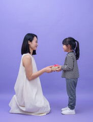 Young Asian mother and daughter on purple background