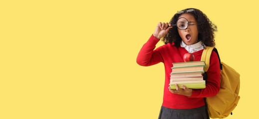 African-American schoolgirl with backpack, magnifier and books on yellow background with space for text