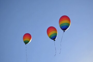 Fototapeta premium Three rainbow balloons are flying in the sky