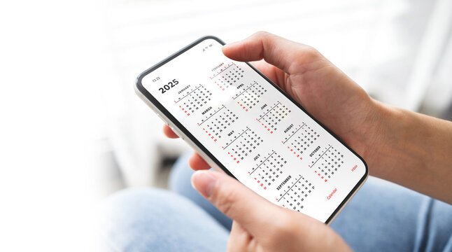 Businesswoman using smartphone with monthly calendar to plan 2025 activities. Scheduling and organizing plans. Technology and business concept.