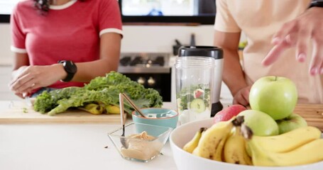 Preparing healthy smoothie, young multiracial couple chopping fruits and vegetables, at home