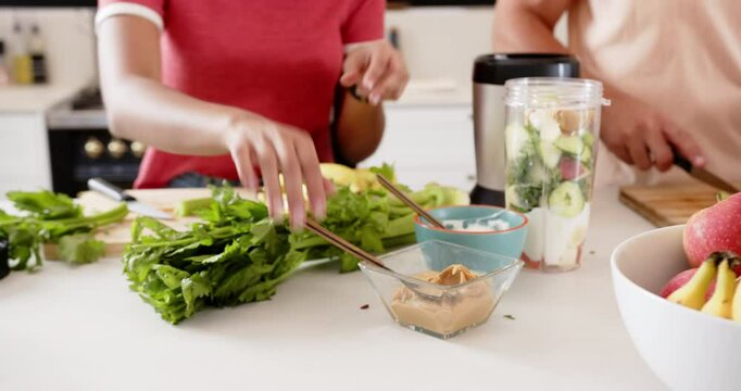 Preparing healthy smoothie, young multiracial couple adding ingredients in kitchen together, at home - Powered by Adobe