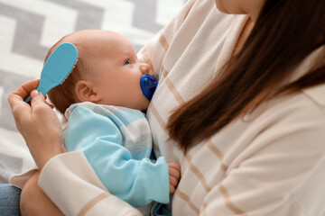 Young mother brushing her little baby's hair with cradle cap in bedroom, closeup