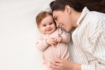 Happy young mother with her baby lying on bed at home