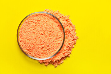 Bowl of orange powder pigment on yellow background