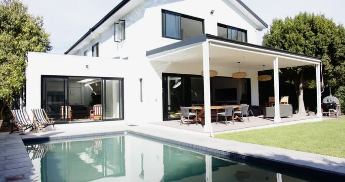 Modern white house with swimming pool and outdoor dining area in backyard