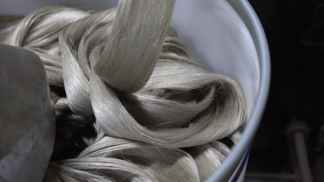 In an industrial setting, linen fibers in a collection container waiting for further processing.