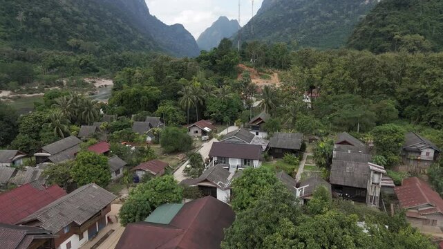 Beautiful flight above a wooden village, Muang Ngoy in Lao PDR. Camera is moving foward above the roofs and the place is surrounded by karst mountains