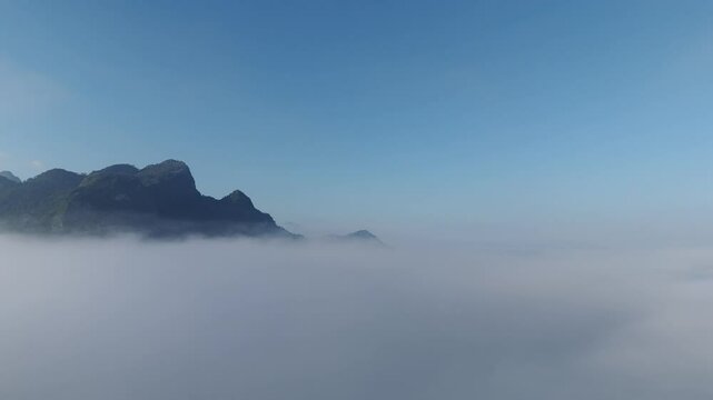 Above the clouds, a drone footage showing sea of clouds and mountains under a blue sky in Luang Prabang province, Lao PDR