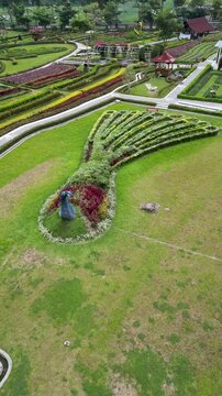 The breathtaking Refugia Garden in Magetan displays vibrant flower arrangements forming a majestic peacock, surrounded by lush greenery and a serene natural backdrop.