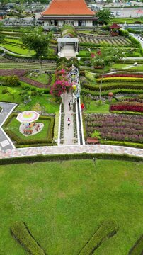Refugia Garden in Magetan boasts vibrant flower beds in stunning patterns, surrounded by lush greenery and set against a serene, picturesque natural backdrop.