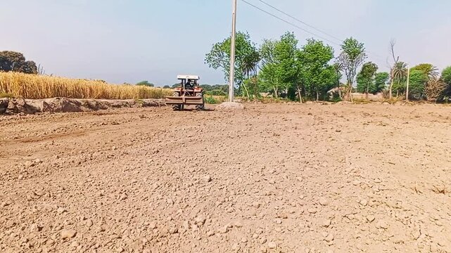 Rahim Yar-khan Punjab Pakistan  Red tractor plowing the field in Pakistan. Pakistani Asian farmer working on agricultural field processing a plowed field, aerial shot. Preparing land