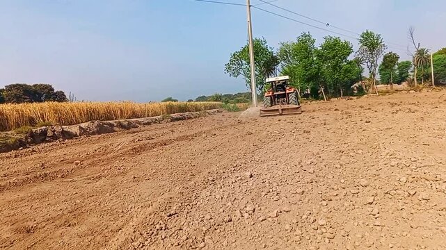 Rahim Yar-khan Punjab Pakistan  Red tractor plowing the field in Pakistan. Pakistani Asian farmer working on agricultural field processing a plowed field, aerial shot. Preparing land