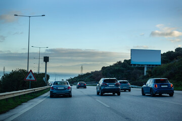 Traffic jam on the highway in the evening with empty billboard.