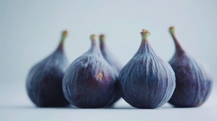 Fresh ripe figs arranged on a white surface with selective focus highlighting their unique texture and color details.