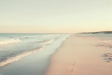 Serene beach landscape with gentle waves and soft sand at sunset.
