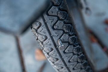 Close-up of a motorcycle tire punctured by a nut.