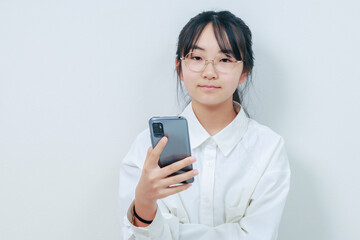 スマホを片手にカメラ目線で微笑む女性