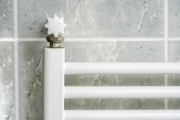 White radiator hung on the wall in a bathroom with green ceramic tiles