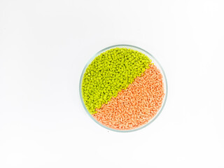 Colorful masterbatch plastic granules in transparent glass cup, polymer carrying pigment poured in white background, suitable for product catalog design of plastic manufacturing industry company profi
