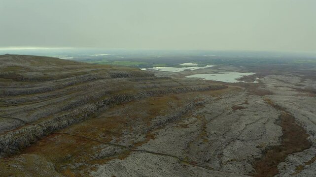 Establishing aerial orbit around Mullaghmore, showcasing a turlough in the background amid The Burren's rocky landscape