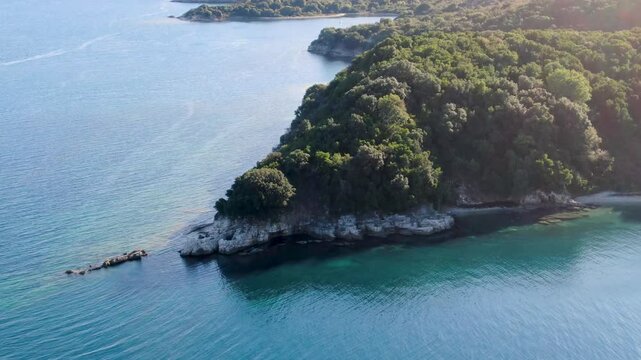 Aerial view of a lush green peninsula jutting into a vibrant turquoise sea. erimitis corfu greece