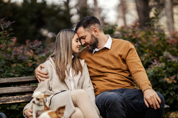 Young romantic dog lover couple on date showing affection and hugging in city park.